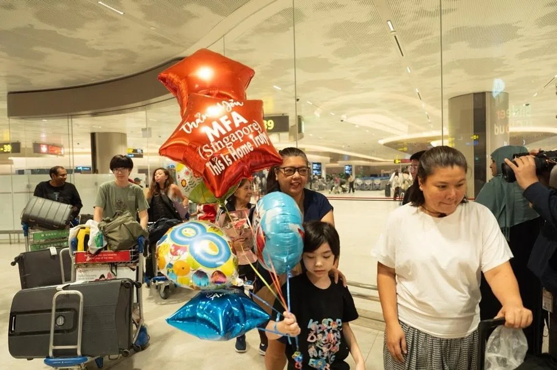 从中东地区乘坐军机安全撤离返回新加坡的一名小朋友，手中拿着一串气球。红色星星的气球上写着：谢谢新加坡外交部，这里才是我们真正的家。