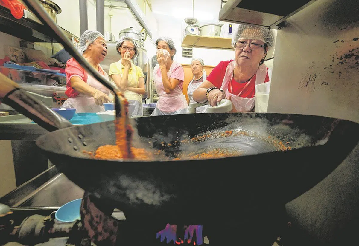  女学员在学做亚参（assam）酱料时都被浓烈的香料味辣得呛鼻，纷纷用布捂住鼻子和嘴巴。（海峡时报） 