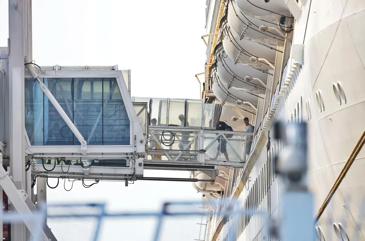  上午8点40分：第一批乘客从游轮出来，通过链接桥前往抵境厅。据了解，每一批约有20人，且都有两名辅警护送到旅游巴士上。（海峡时报） 