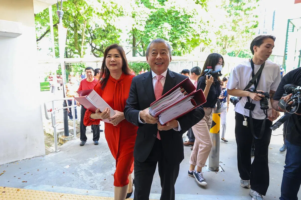 吴振华（前排右）到选举局提交总统候选人合格证书申请表格当天，妻子李丽恩（前排左）总是在一旁替他拿着厚厚的文件夹。（联合早报）
