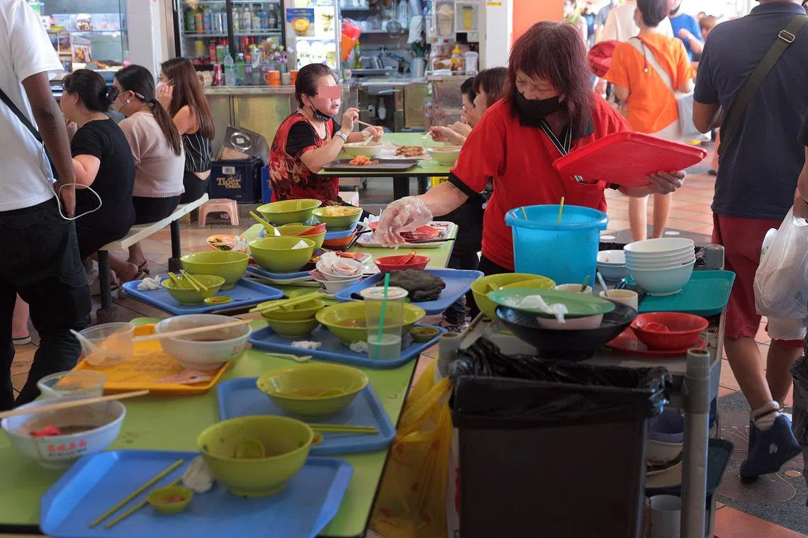 新加坡人在小贩中心用餐后，都没有收拾桌子归还托盘餐具的习惯。（海峡时报）