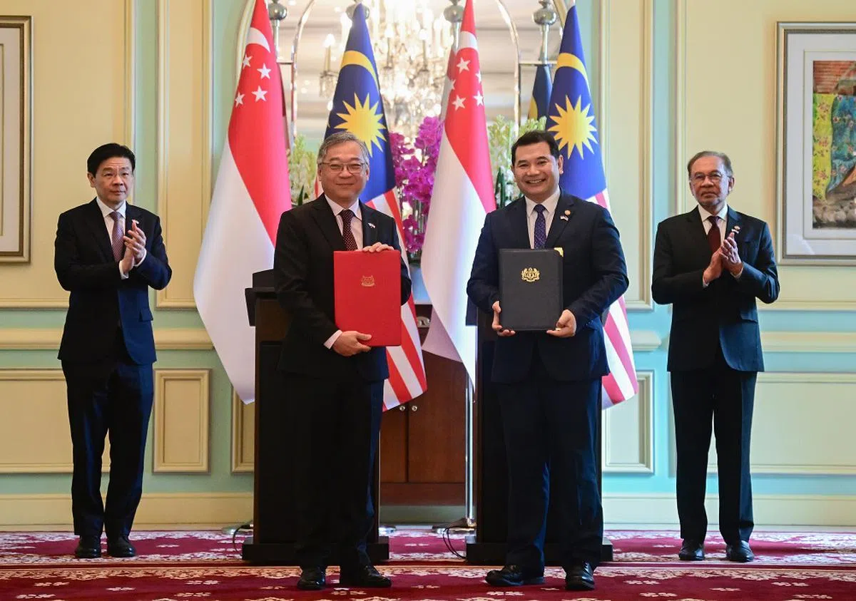 新加坡副总理兼贸工部长颜金勇（左二）和马国经济部长拉菲兹（右二）在黄循财（左一）及马国首相安华（右一）的见证下，完成柔新经济特区协定的签署。（海峡时报）