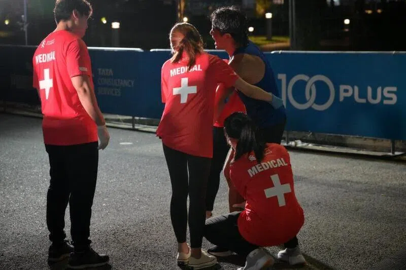 2024年新加坡渣打马拉松，一名半程跑者冲过终点后接受医护人员帮助。