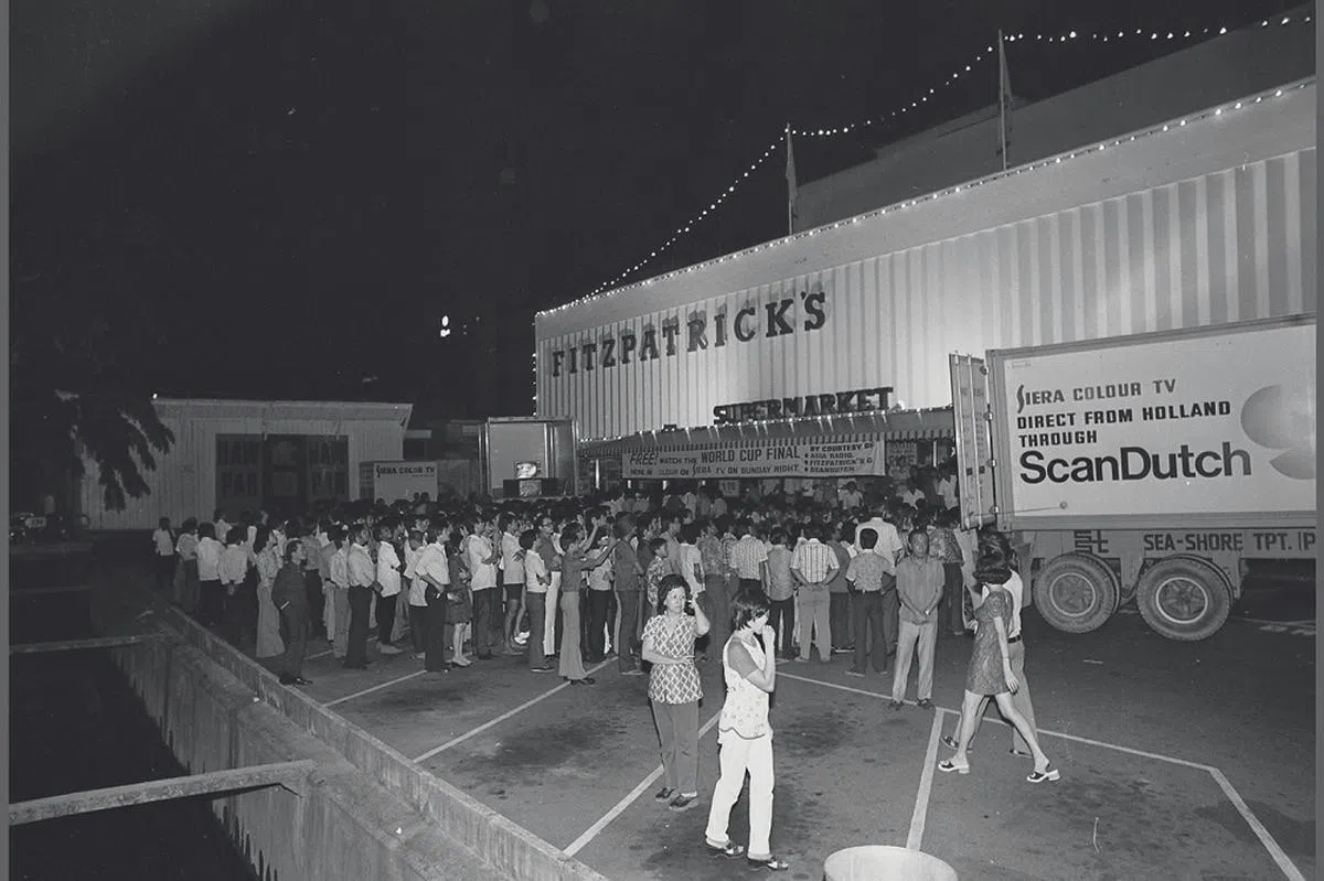 足球迷在菲士吧特超级市场外的停车场聚集，等待收看彩色直播的1974年世界杯决赛。球赛在晚上10点20分才开始转播，但许多想要找个好位置的球迷，早在傍晚7点就已经到场。（海峡时报档案照）