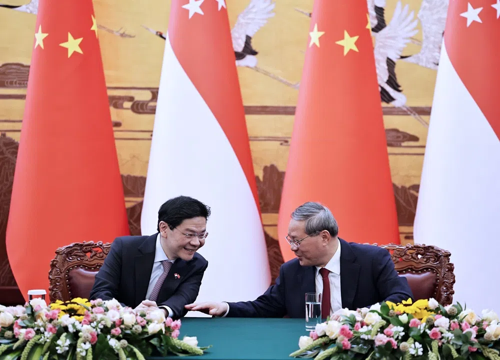 在黄循财总理（左）和中国总理李强的见证下，新中两国6月23日签署四项合作文件，在第三方国家培训、智慧产权数据分享、高层官员交流等方面加强合作。图为二人在签署仪式上互动。（海峡时报）