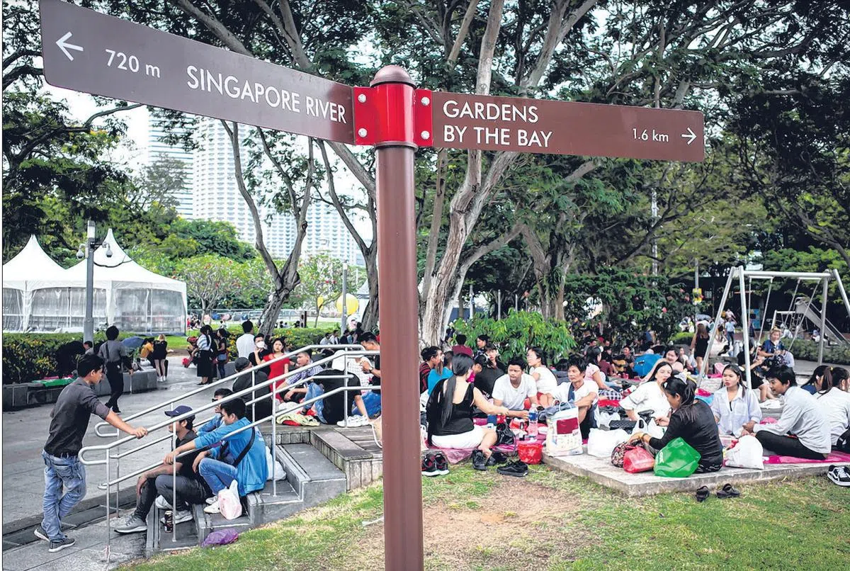 星期天的海滨公园，是帮佣和客工相约团聚的“老地方”，大家会在草地上铺上草席一起享用家乡菜。（联合早报）
