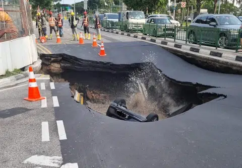 7月26日下午约5时，丹戎加东南路和蒙巴登路的交界处，一辆马自达汽车掉落进积满水的坑洞。（脸书截图）