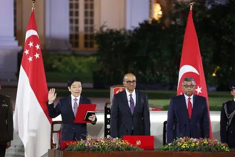 新加坡第四位总理黄循财（左）举起右手，在尚达曼总统（中）见证及大法官梅达顺（右）的主持下，宣誓就职。（联合早报）