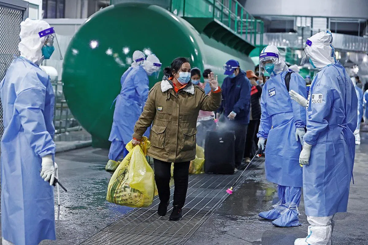 康复后获允许“出院”的冠病患者们，完成消毒后拿着个人物品，步出这个由上海国家会展中心改建而成的临时医院。（路透社）