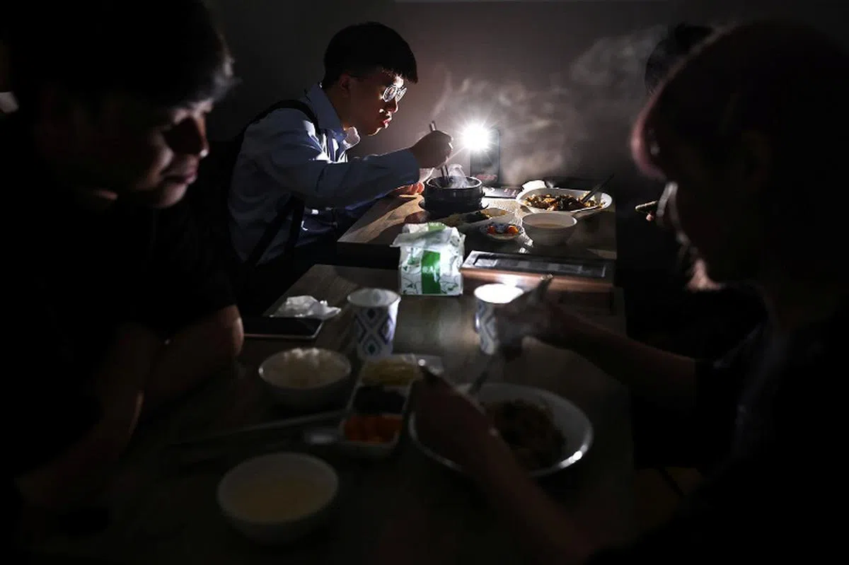  台湾5月13日全岛多处停电，民众“暗地里”掏出手机照亮餐桌继续用餐。（路透社） 
