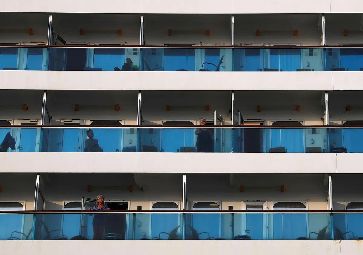  游轮在靠岸之后，只有少数工作人员通过链接桥进出游轮。不少游轮上的乘客在靠岸后纷纷望向船外。（海峡时报） 