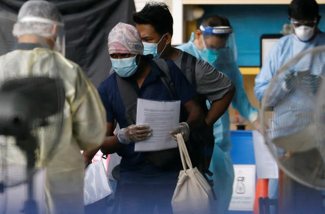 全副武装的前线人员在爆出感染病例的西雅兀兰客工宿舍进行转移客工至隔离设施的工作。（路透社）