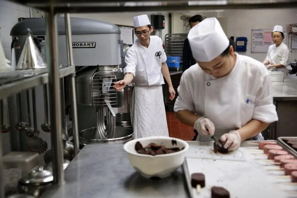  丽晶酒店的厨房内，员工们在切割和搅拌时都自动自发采用了安全措施。（海峡时报） 