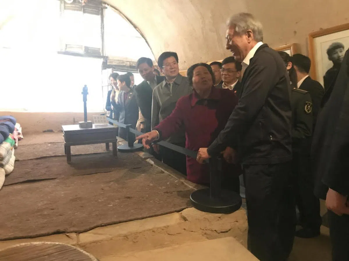 4月15日，访问中国的我国副总理兼国家安全统筹部长张志贤（右一）、贸工部长陈振声（右四）等新加坡政治职务担任者，在延安梁家河村参观中共总书记习近平1969年到1975下乡期间住过的一个窑洞，一名女村民（右二）向张志贤介绍洞里的设施和生活情况。（联合早报） 