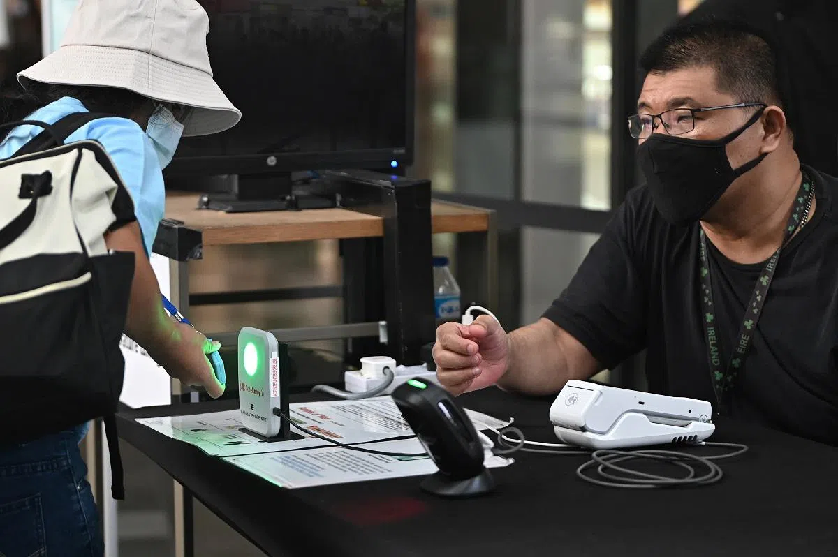 在我国疫情警戒级别持续为橙色期间，大家去到哪里都必须扫描“合力追踪”手机应用。（海峡时报）