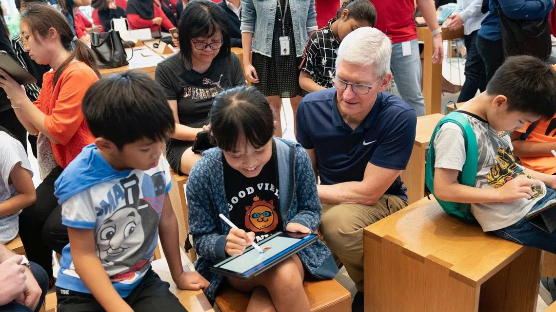 苹果执行长库克（右一）在新加坡乌节路的苹果旗舰店与小顾客们互动。（库克推特）