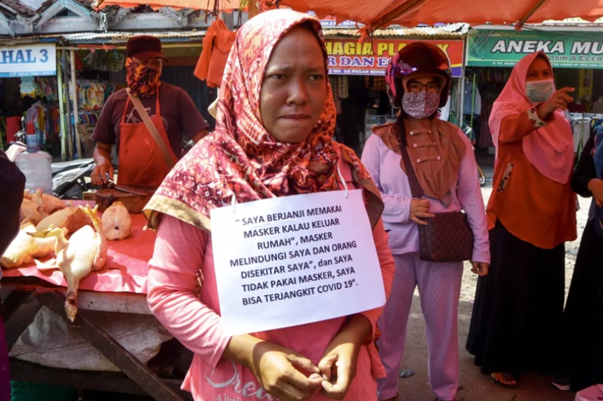  女子胸前挂着“我一定会戴口罩”的牌子。（法新社） 