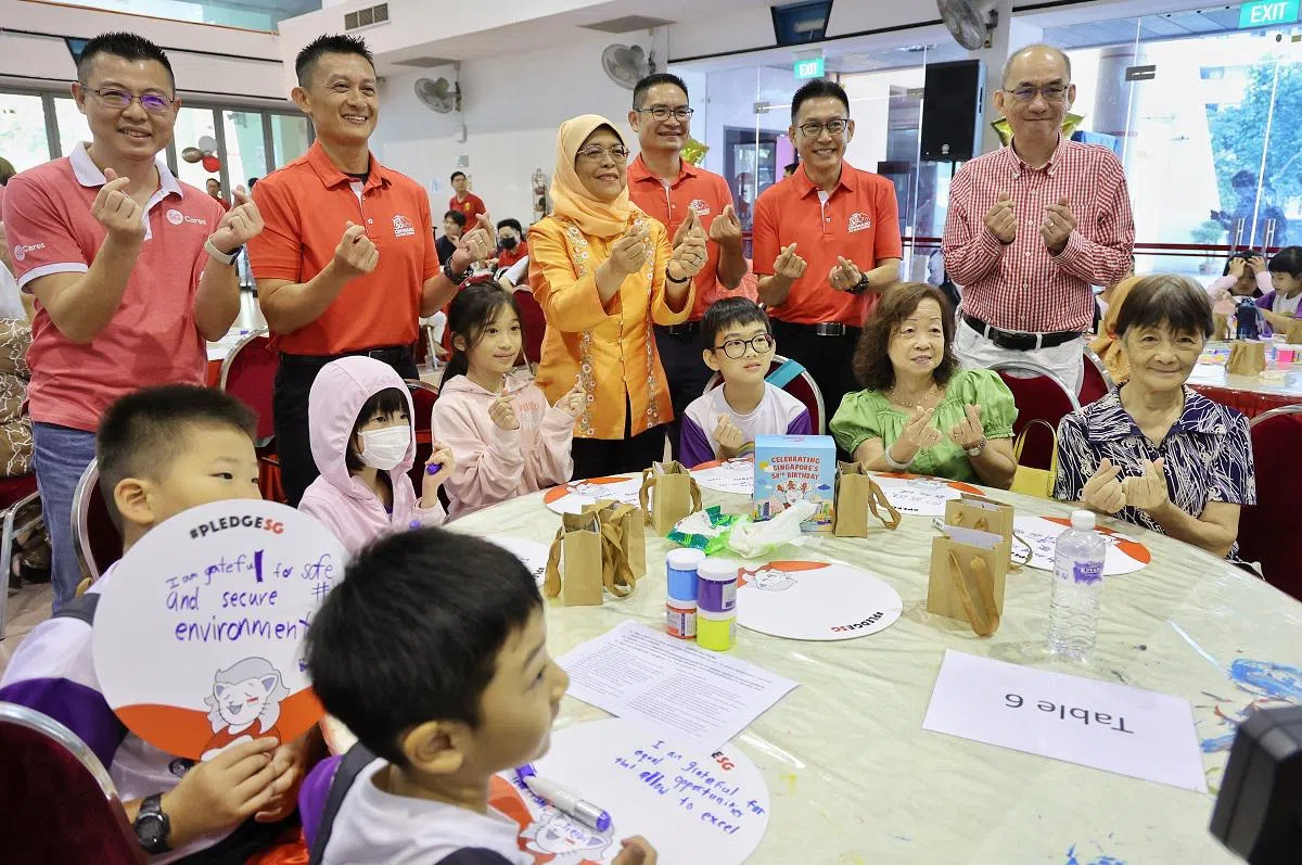 2023年配合国家生日，新加坡国庆庆典筹委会开展志愿服务运动，鼓励民众加入义工行列，帮助有需要的群体。前总统哈莉玛（站立者，中）联同国庆庆典筹委会、关爱新加坡、飞跃社区服务等代表，同参与活动的居民和学生合影。（联合早报）