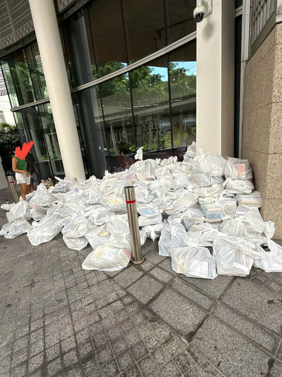 数百本书籍被装入白色塑料袋，一袋袋的书籍堆叠在上下车接送处，引人侧目。 （海峡时报读者提供）