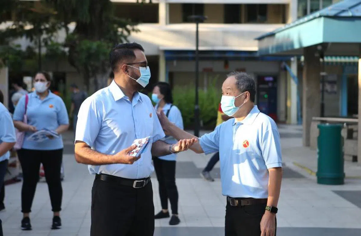 卸下战袍的刘程强（右）在2020年大选仍戮力为工人党助选。左为毕丹星。（联合早报）