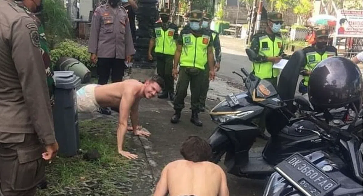  因未佩戴口罩而被罚做俯卧撑的外国游客。（联合早报） 