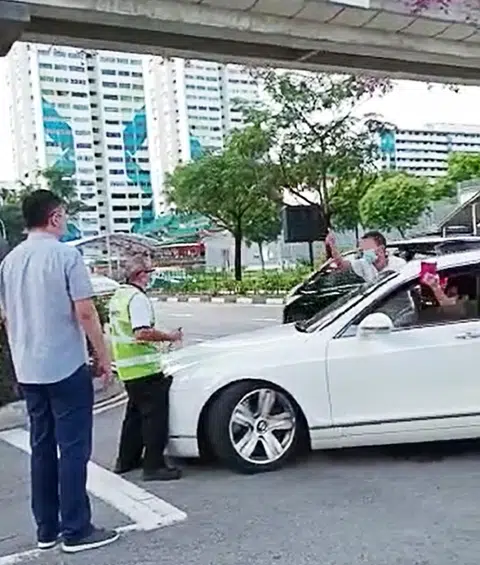 试图硬闯卍慈学校的61岁宾利车“爷爷”（右二）与62岁的保安员梁亚发（左二）正在校门口对话。（视频截图）