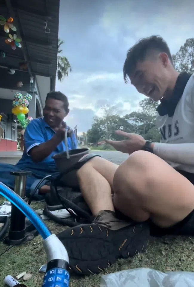 伊萨（左）尝试帮Joel Liu（右）修好脚踏车的轮胎。