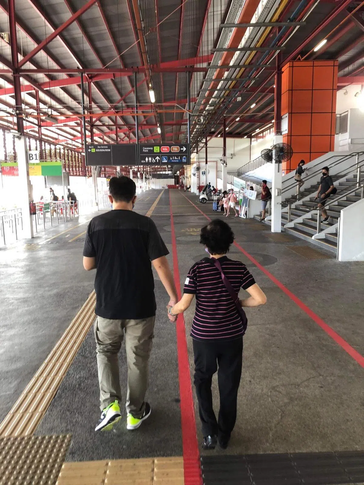 弟弟牵着年过八旬的妈妈。（卢丽珊摄）