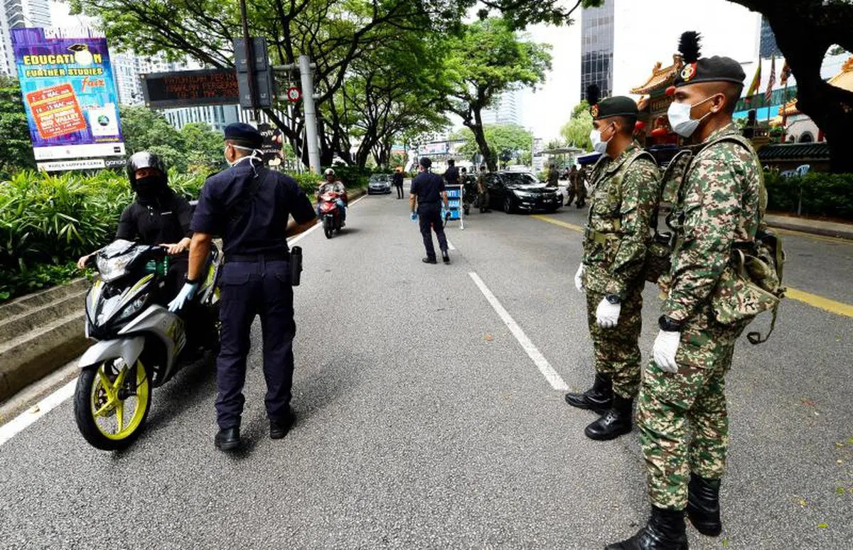  马国政府去年三月正式派出军队配合警方执行行管令，确保民众留在家里共同防疫。图为军警在吉隆坡检查过往车辆。（星报） 