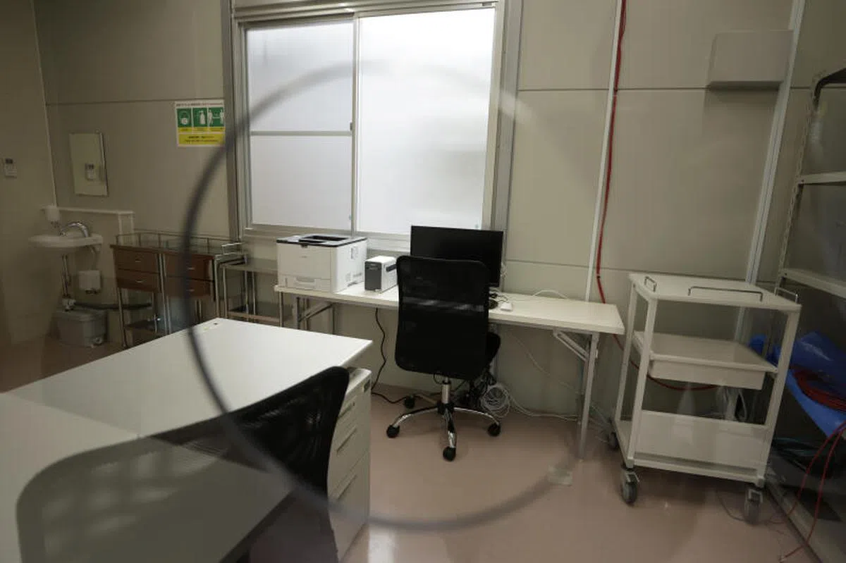  驻守在发烧筛检站的医生将透过玻璃洞口处理检测工作。（彭博社） 