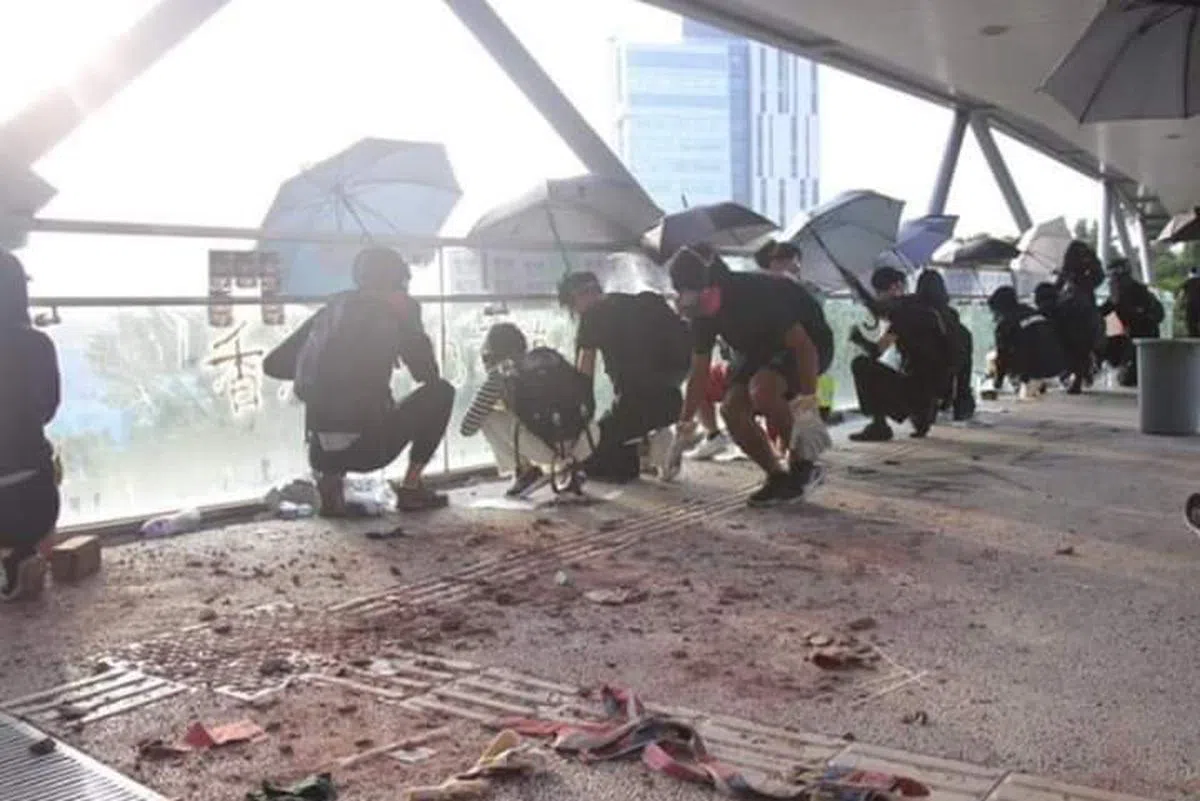  警员向天桥开枪，黑衣人用雨伞遮檔。（我爱旅行面簿）  