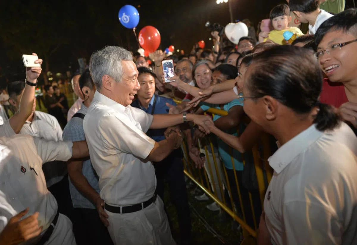  行动党每四五年都要面对一人一票的民主选举，让全民打分。图为李显龙总理在2015年的一场大选竞选活动中与支持者握手。（海峡时报） 