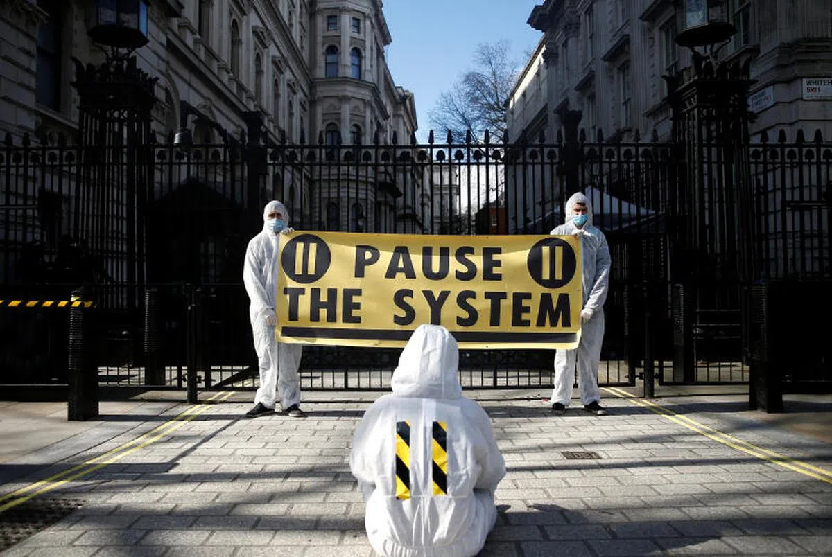  手持“停止防疫法”布条的英国民众在街头示威抗议。（路透社） 