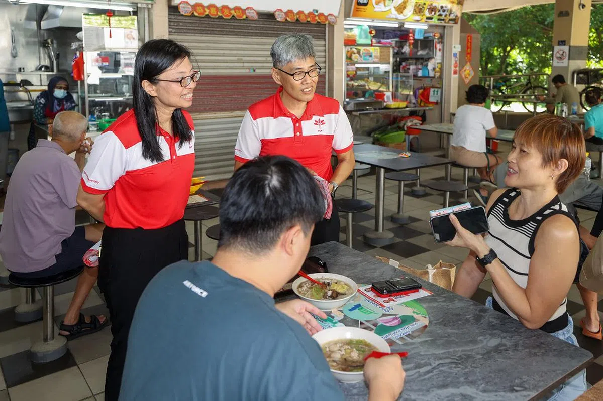 潘群勤（左）在也是前进党党员的丈夫陈礼添的陪同下，到宏茂桥4巷走访选民。（联合早报）