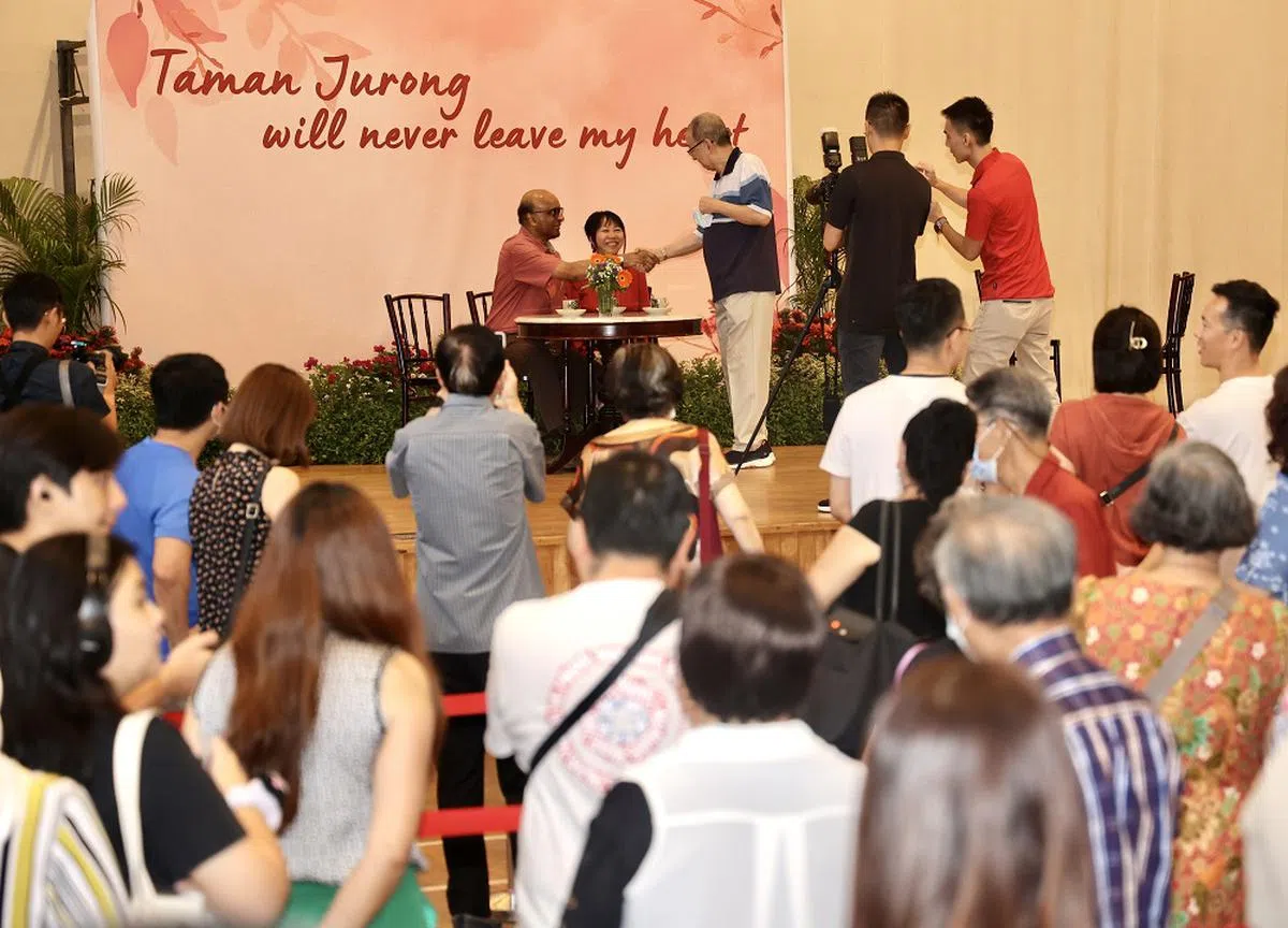 国务资政兼社会政策统筹部长尚达曼（台上左一）7月7日卸下公职不再担任裕廊集选区议员。数千名居民和公众在6月24日出席与尚达曼叙别的活动，排队与他和夫人珍一藤木（台上左二）合照。（联合早报）