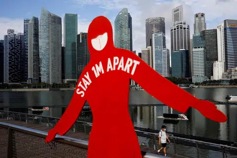 滨海湾金沙外提醒公众戴好口罩，保持一米安全距离的防疫告示。（路透社）