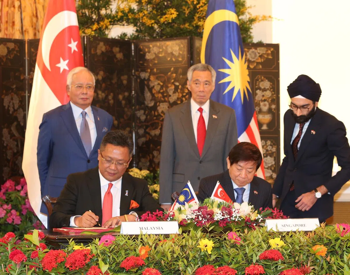  李显龙总理（后排右）与马来西亚首相纳吉（后排左）见证了新柔地铁系统（RTS Link）双边协定签字仪式。代表双方签字的分别是基础建设统筹部长兼交通部长许文远（前排中），及马来西亚首相署部长阿都拉曼达兰（前排左）。（早报网） 