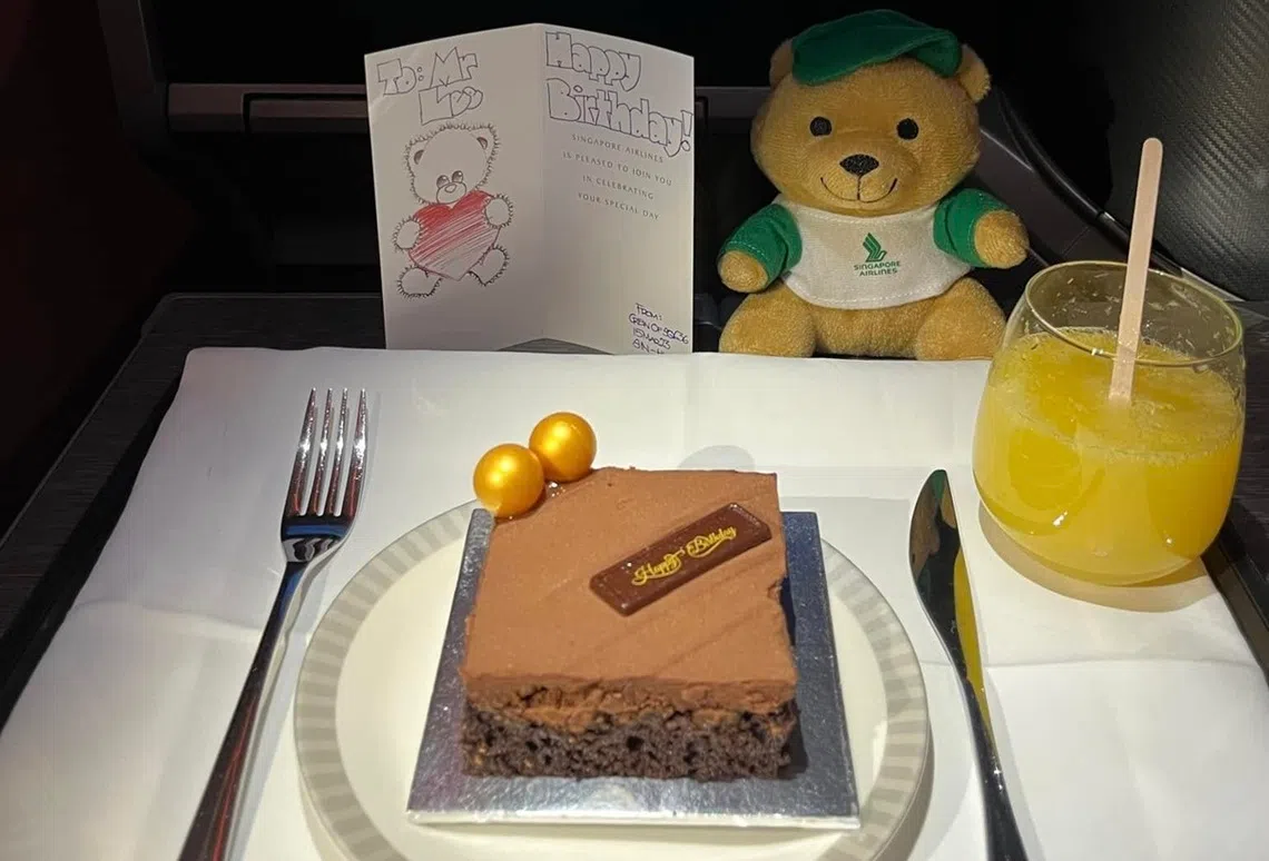 除了蛋糕，新航还给这位庆生的乘客送上一张机组人员签名的贺卡，和一只玩具熊。
