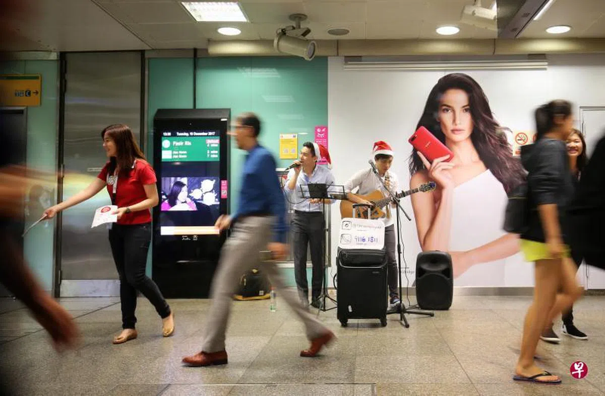  配合即将到来的圣诞节，SMRT特别邀请街头艺人和团体到地铁站内表演助兴，职员也向乘客分发圣诞贴纸。（联合早报） 