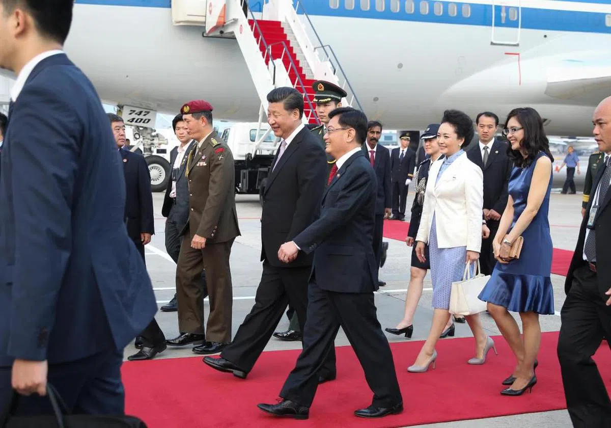  新中建交25周年，中国国家主席习近平于2015年11月6日抵达新加坡进行国事访问。习近平主席（红地毯上者左一），由新加坡财政部长王瑞杰（左二）以侍从部长的身份负责接机。习近平夫人彭丽媛（右二）则由王瑞杰夫人章慧霓（右一）陪同。（海峡时报） 