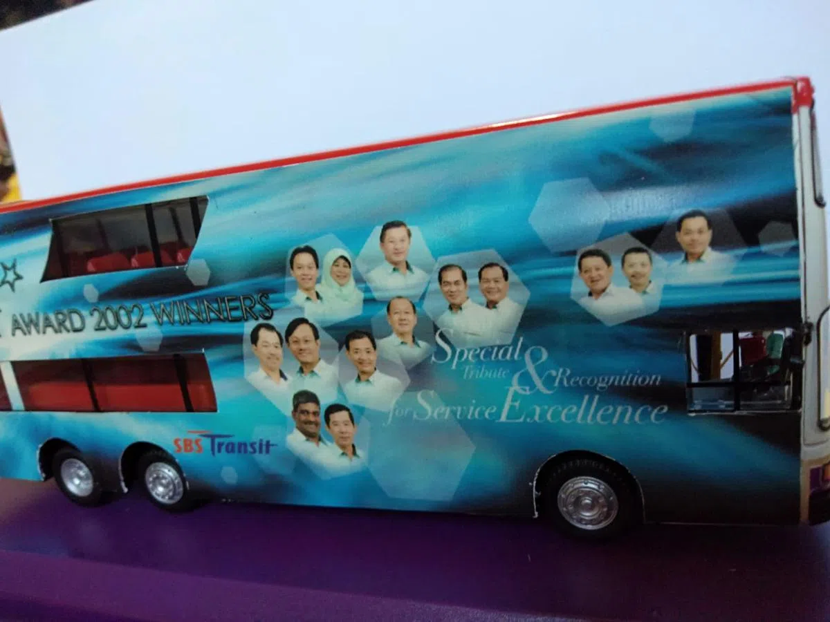  许燕安(中）的模范服务在2002年赢得了认可，公司把得奖者印在巴士上祝贺他们。（新捷运面簿） 