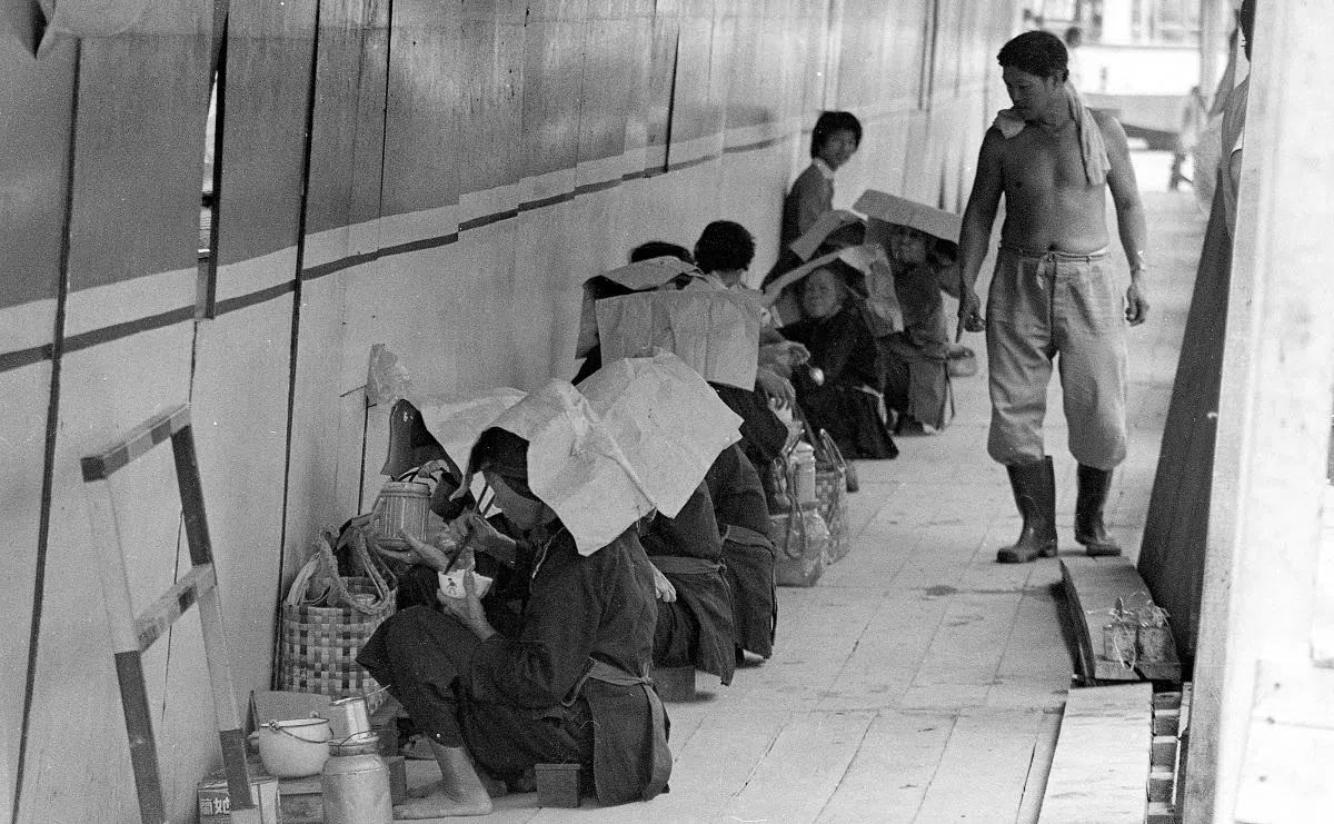 1982年，一排红头巾在克罗士街附近的工地吃午餐。（The Singapore Monitor）