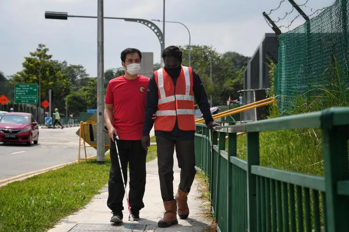  视障人士协会图书馆的员工Kelvin（左）与客工玛尼甘丹。他们正前往附近的新加坡视障人士协会，客工平时也协助引导地铁站的乘客。（海峡时报） 