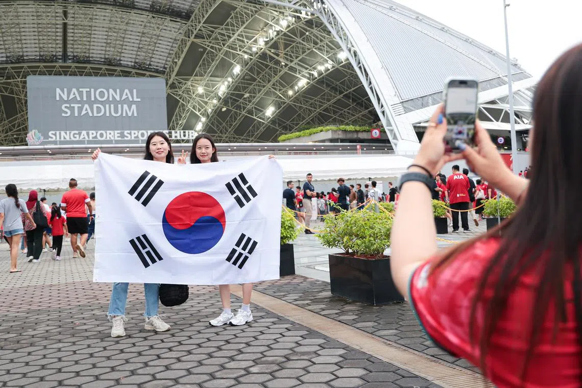 韩国球迷在今年6月，韩国对垒新加坡的世界杯亚洲区外围赛开始前，在国家体育场外合照留念。（联合早报）