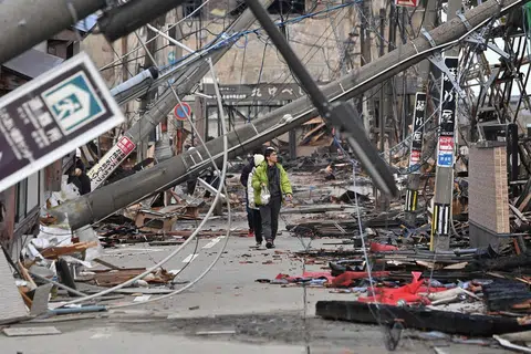 日本石川地震重灾区轮岛市，灾民走在一片废墟中。（法新社）