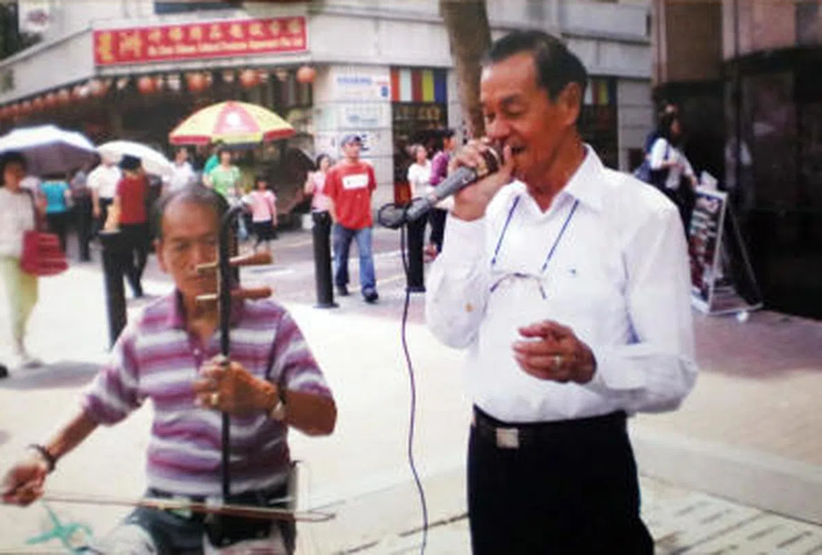  李超群以前街头卖艺时的照片，握着麦克风唱歌的就是李超群。（联合早报） 