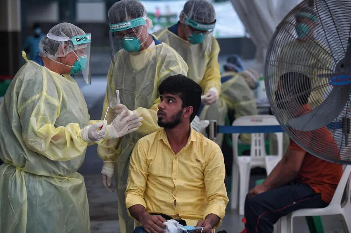  医护人员为一名客工进行冠病检测。（海峡时报） 