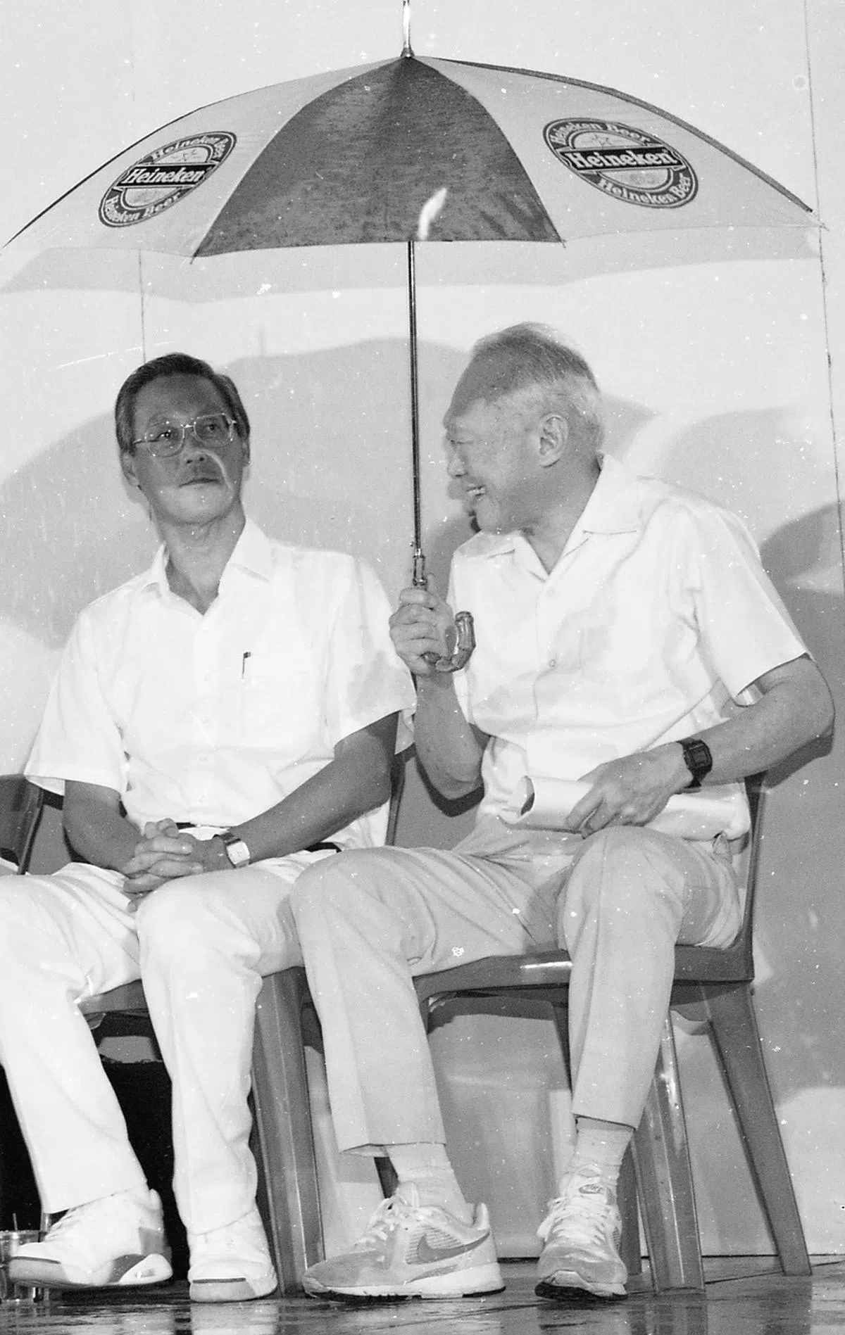人民行动党在1992年的马林百列集选区补选时举行的一次群众大会突然下起雨来。当时的李光耀资政（右）撑着伞与战友吴作栋一起遮雨。（联合早报）