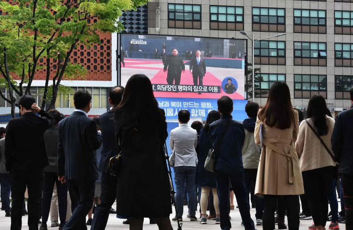  韩国总统文在寅和朝鲜领导人金正恩在板门店的历史性会晤，韩国各大媒体都进行了现场直播。许多韩国民众在户外驻足观看。（法新社） 