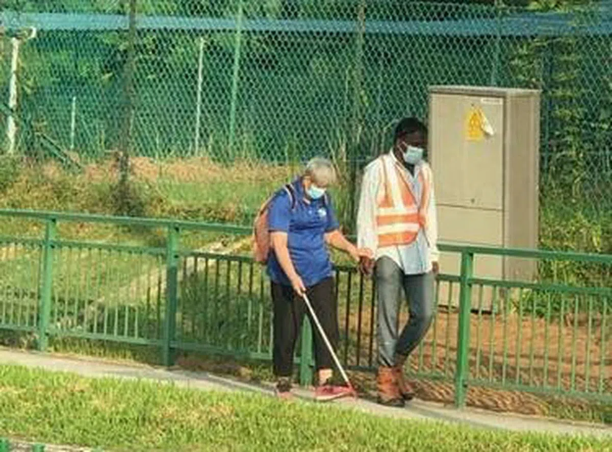  善心客工扶着视障人士过马路。（Stomp） 